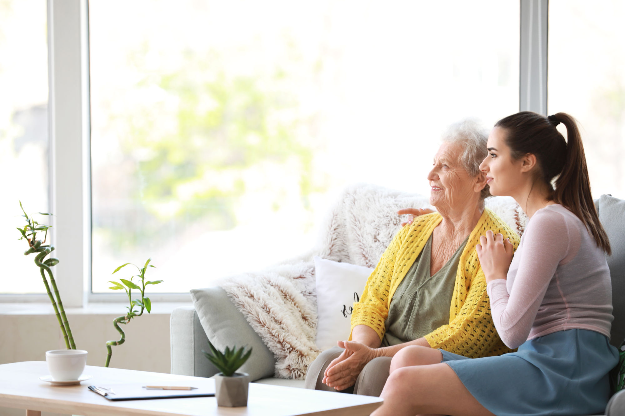 Full indoor shot of a young woman supporting an older woman.